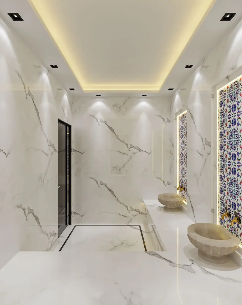 Beyaz mermer yüzeyler, mozaik duvar detayları ve oturma alanıyla tasarlanan modern hamam iç mekânı