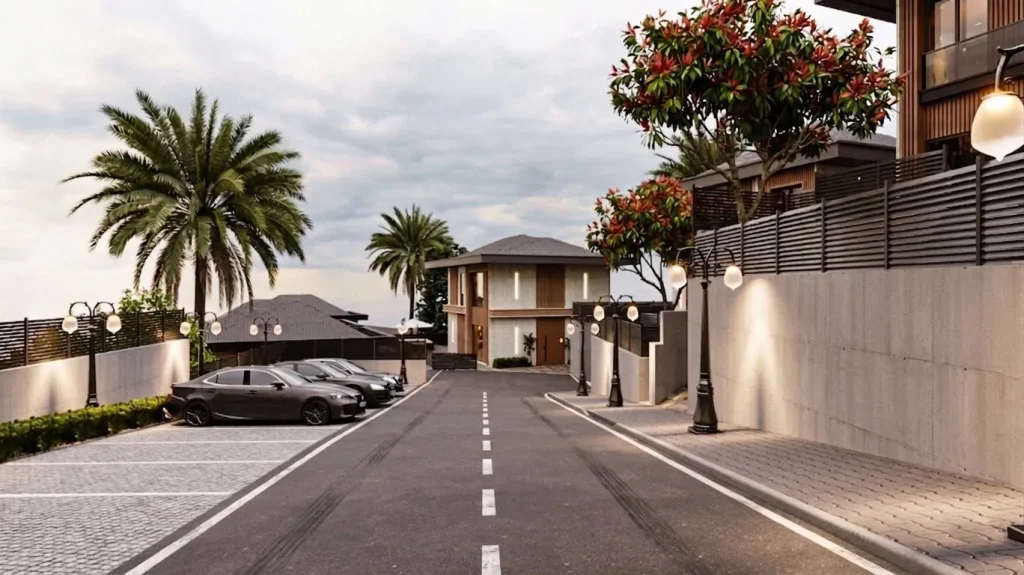 Modern villalar, açık otopark alanları, düzenli araç yolu, dekoratif aydınlatmalar ve palmiye peyzajı bulunan lüks villa sitesi